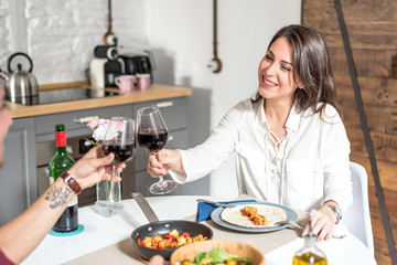 Happy young couple eating and drinking wine at home