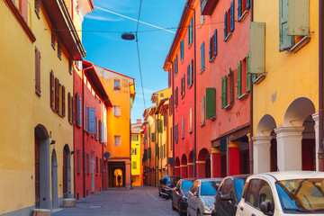 Obraz premium Medieval street portico with bright colored houses in the Old Town in the sunny day, Bologna, Emilia-Romagna, Italy