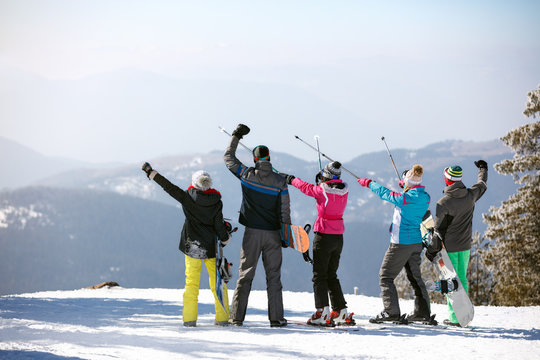 Skiers in mountain with ski sticks up, back view