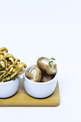 Seasonal mushrooms melange with thyme. White background, white bowls. Isolated. Close up.