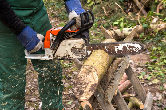 Mann mit Motorsäge sägt Holz für Kamin Brennholz Arbeit