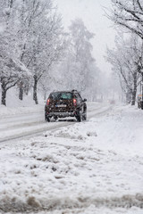 Verschneite Straße und Auto, Wintereinbruch