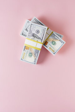 Overhead view of stack of 100 dollar bills on pink background