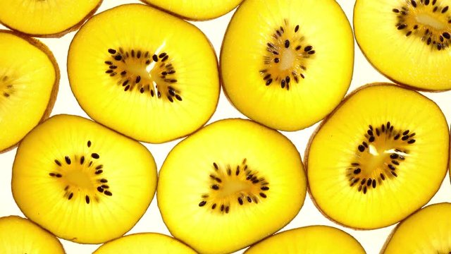 Excellent top view of sliced golden kiwi fruit in flat lay close up, rotating clockwise. Amazing natural background with vibrant texture and backlight in 4k, 3840x2160, clip. Beautiful dessert.
