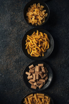 Different kind of pasta on dark background