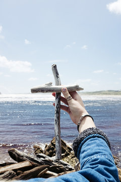 Teen girl holding a cross made form two pieces of driftwood