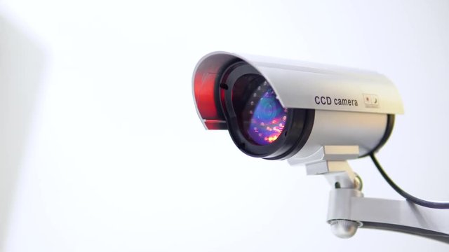 The surveillance camera with flashing red light on white background. Close up