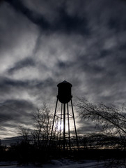 Water Tower Silouette - Vertical image showing an old water tower in Newport Maine with the sun...