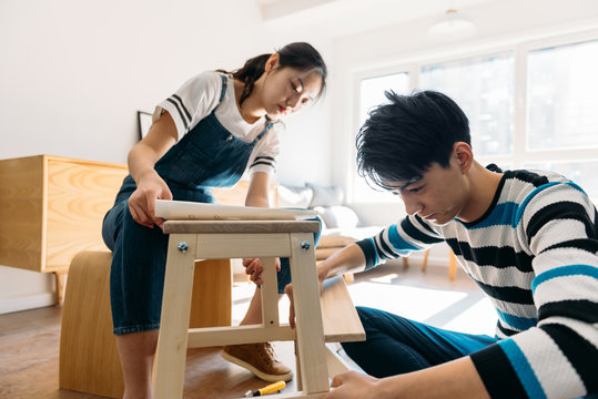 Young couple assembling flat-pack furniture