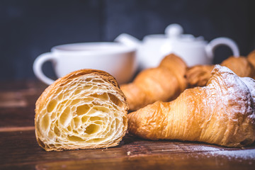 A cut croissant and a croissant with sugar powder lie side by side. - 187028041