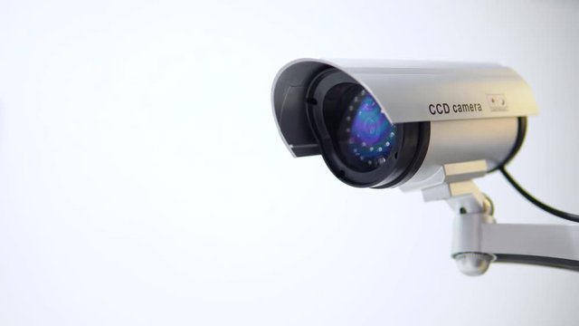 The surveillance camera with flashing red light on white background. Close up