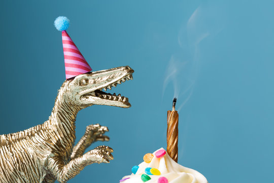 Birthday cake and toy dinosaur against blue background