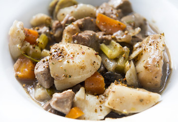 a bowl of beef stew with potatoes, carrots, celery, mushrooms and onions is shown