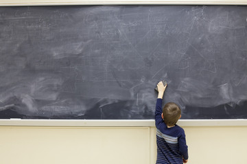 Five year old boy erases blackboard
