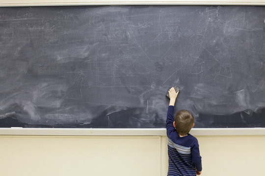 Five year old boy erases blackboard