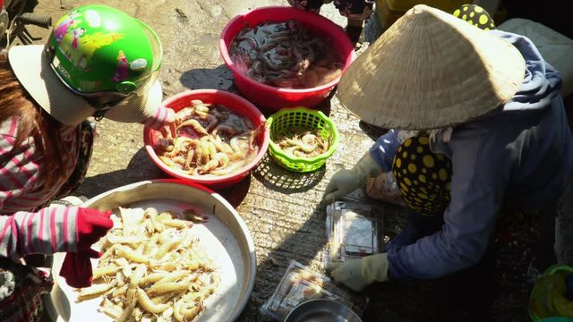 Local people working at marketplace, woman is selective fish. woman cleans and prepares fish for sale at fish market. Vietnam. cutting fish
