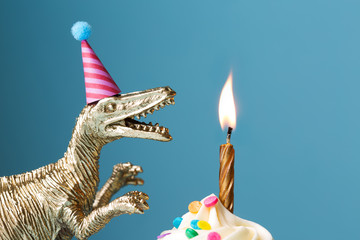 Birthday cake and toy dinosaur against blue background