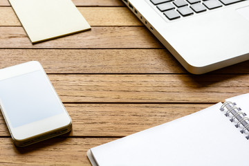 Neat wooden desktop with smartphone, laptop, notebook and notepad.