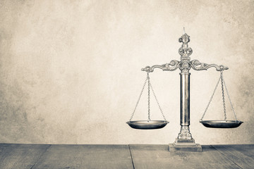 Retro law scales on wooden desk front concrete wall background. Symbol of justice. Vintage old style sepia photo