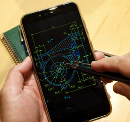 engineer working on mechanical piece scheme on mobile device