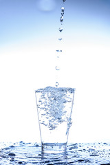 Pouring water and splashing in the glass with reflection on mirror.