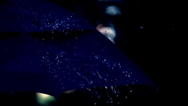 Black umbrella in the rain. Slow motion.