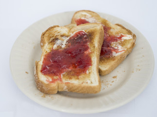 Toasted white bread is shown with jam and margarine
