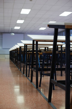 Rows of tables and stools in a large classroom with nobody