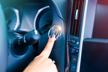 Woman driver pushing a start ignition button in the car