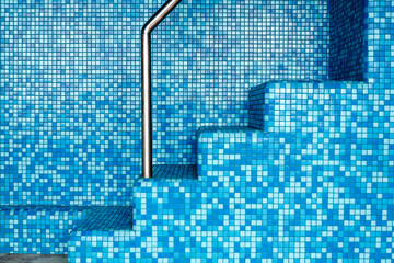 The steps in the pool with blue tiles
