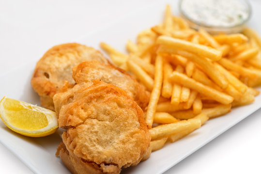 fish and chips with lemon and sauce on white plate