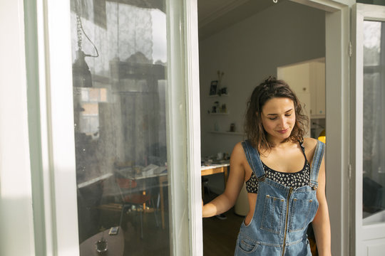 Young woman dressed sexy in dungarees standing in her living room