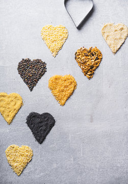 Various dried food groups in the shape of hearts on a concrete background.