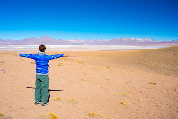 Tourist looking at the stunning landscape of salty frozen lake on the Andes, road trip to the famous Uyuni Salt Flat, travel destination in Bolivia.