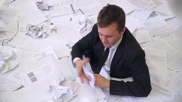the man in the office drowning in paper