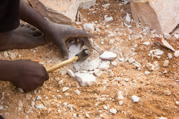 Ugandan child's hands breaking rocks into small slabs for his or her foreman. Shot in Uganda in...