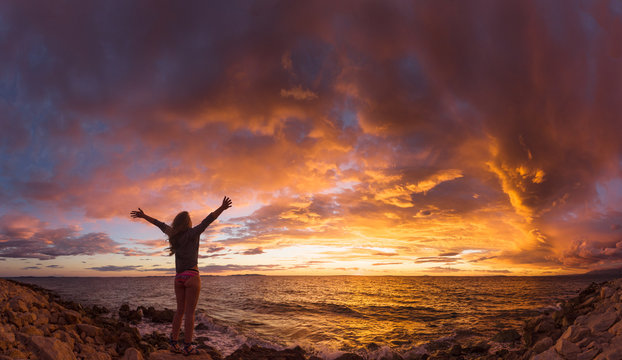 Female standing on the sea shore admiring the spectacular sunset