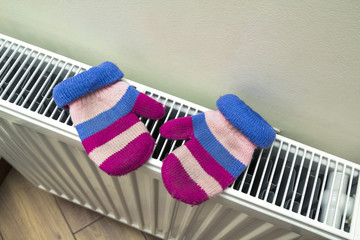 Children's warm hand knitted striped woolen gloves drying on hea