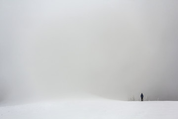 Obraz premium Far away lonely figure of a man standing outdoors in winter
