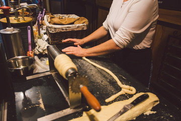 The hands of a female baker cook trdelnik or Trdlo national treat in the Czech Republic in winter