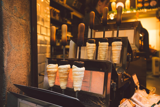 Traditional street food of country Czech Republic. Preparing of Trdelnik - traditional czech bakery. Czech sweet pastry called Trdlo. Trdelnik baking on the street market in Prague