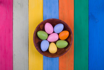 Easter, colored eggs in a basket on a colored wooden table