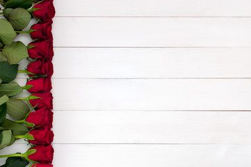 Top flat view of red roses on a white wooden surface (concept, copy space)