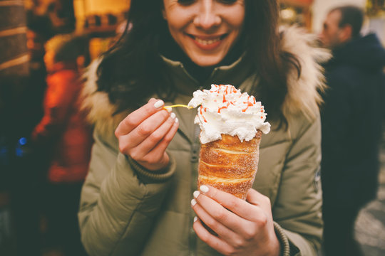 trdelnik or Trdlo with cream in the hands of a beautiful winter girl in the Czech Republic, Prague at the Christmas market