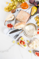 Sandwiches with ricotta or cream cheese, ciabatta, fresh figs, pears, grape, walnuts and honey on white marble table table, with wine glass copy space top view