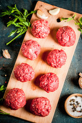 Raw meatballs with olive oil and spices on dark concrete table, top view copy space