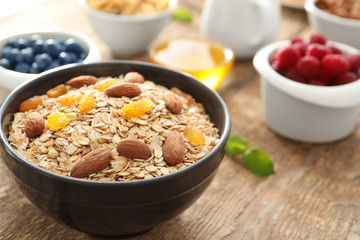 Bowl with oatmeal flakes, raisins and almond on wooden background