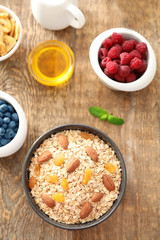 Obraz na płótnie Canvas Bowl with oatmeal flakes, raisins and almond on wooden background