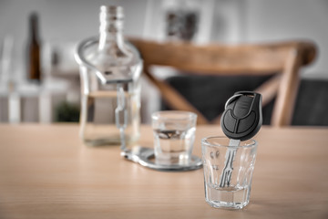 Car key in glass with alcohol on wooden table. Don't drink and drive concept