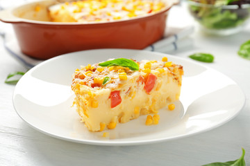 Plate with piece of corn pudding on table